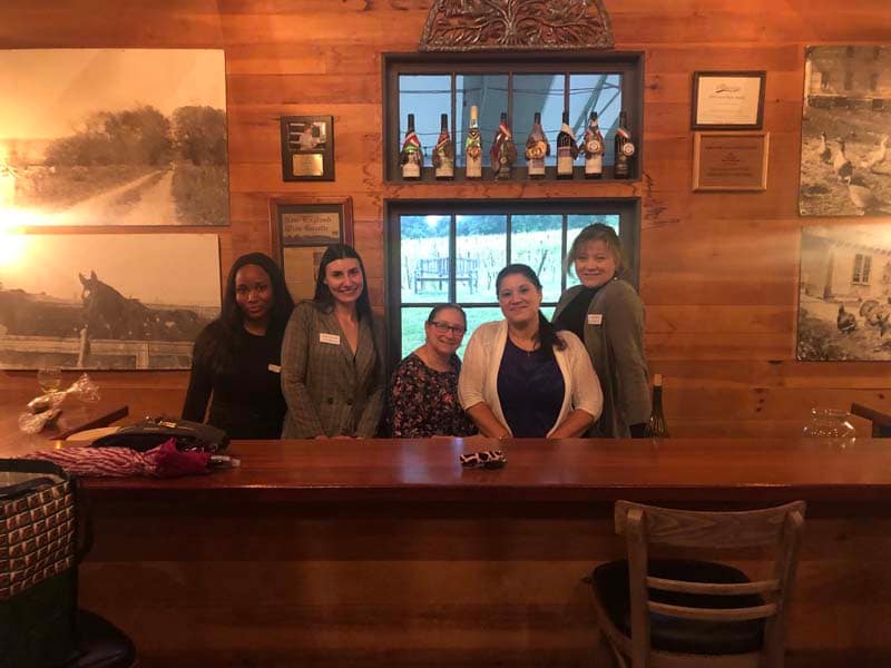 women-posing-behind-bar-at-vineyard-event